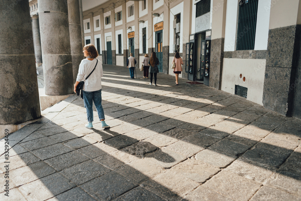 Young woman tourist walking in the columns of Piazza del Plebiscito