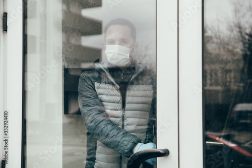 Covid-19 outbreak themed image. Male with mask and gloves leaving his home in quarantine time. Stay at home. 