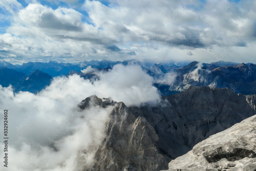 Sharp and rocky mountains range at Austrian-Italian border. There s a path mark on a stone. Serenity and peace. Clouds breaching high mountains. Lots of loose rocks, possibility of landslide