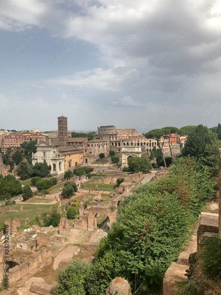 Natural landscape of Italian vegetation under sunny barely cloudy sky against the background of Roman ruins on the horizon.