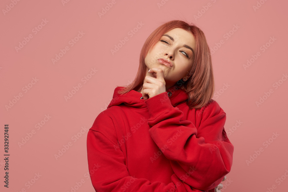 Pensive young woman in red sweatshirt isolated empty pink background Pensive young woman in red sweatshirt isolated empty pink background