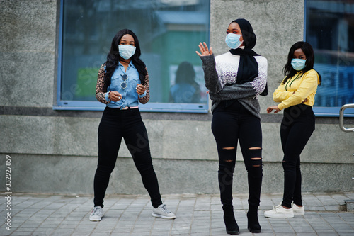 Group of three african american young volunteers wearing face mask outdoors. Coronavirus quarantine and global pandemic.
