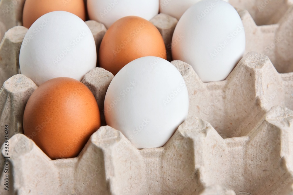 Brown and white chicken eggs in cardboard egg tray. Organic egg for healthy protein breakfast. Easter symbol. Raw chicken eggs. Brown and white chicken eggs in cardboard egg tray. Organic egg for healthy protein breakfast. Easter symbol. Raw chicken eggs.