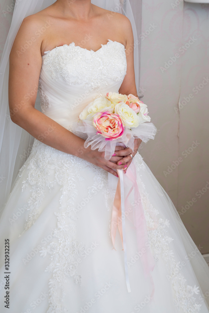 Naklejka premium The bride holds a beautiful wedding bouquet of pink and white flowers in her hands