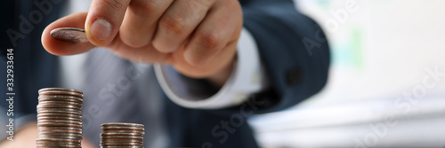 Male hands in suit stack coins on table, saving