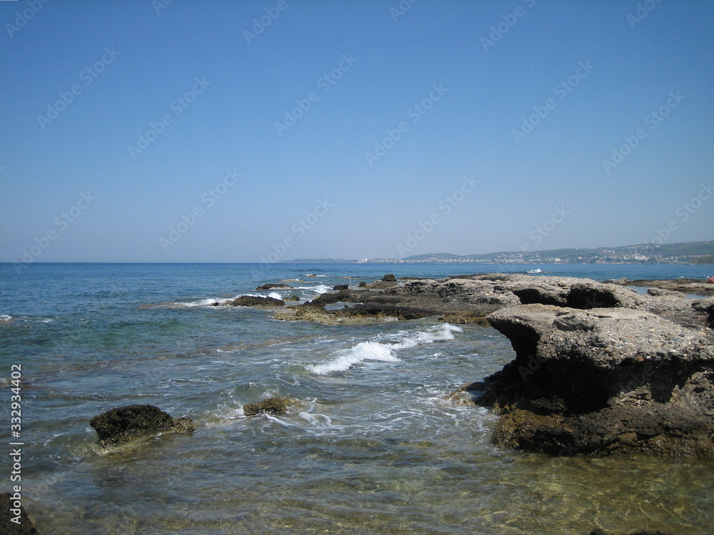 Weak waves gently wash the stones lying on the shallow bottom of the sea rocky shore in good weather. Weak waves gently wash the stones lying on the shallow bottom of the sea rocky shore in good weather.