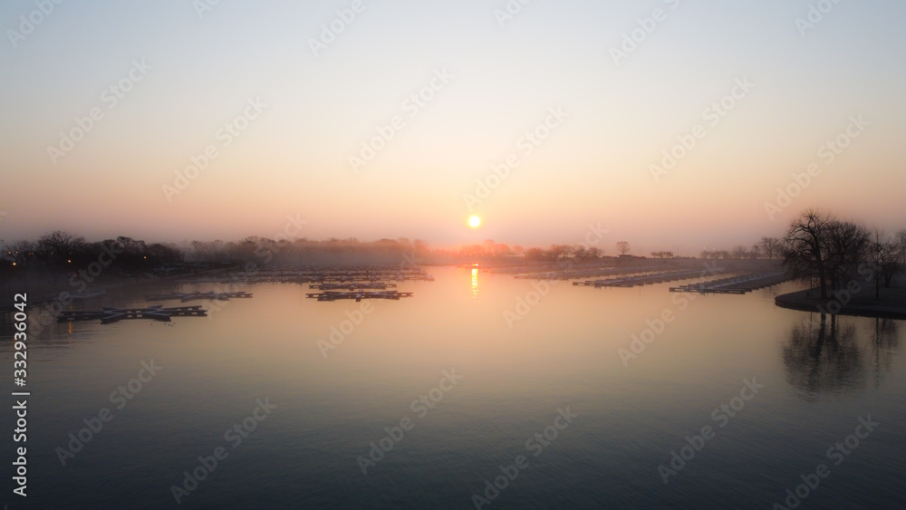 Epic wide angle shot of empty boat docks and calm water as the sun rises over fog covered trees in Chicago Illinois in the early morning