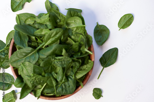 Fresh spinach in a wooden bowl isolated on white background