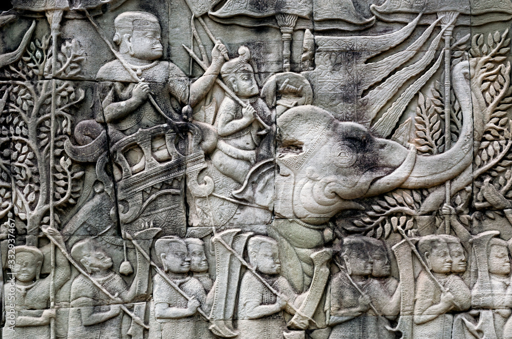 Army with Khmer soldiers and elephants on the 12th century relief of Bayon temple, Cambodia. Historical artwork on wall of the landmark in Angkor. UNESCO world heritage site
