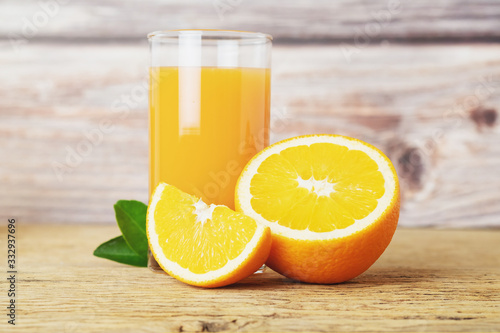 Glass of fresh orange juice with fruits cut in half and sliced with green leaf on wood background