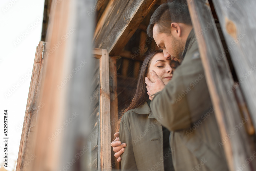 couple in love looks out of the window, wooden house. The concept of buying new housing for young families. couple in love looks out of the window, wooden house. The concept of buying new housing for young families.