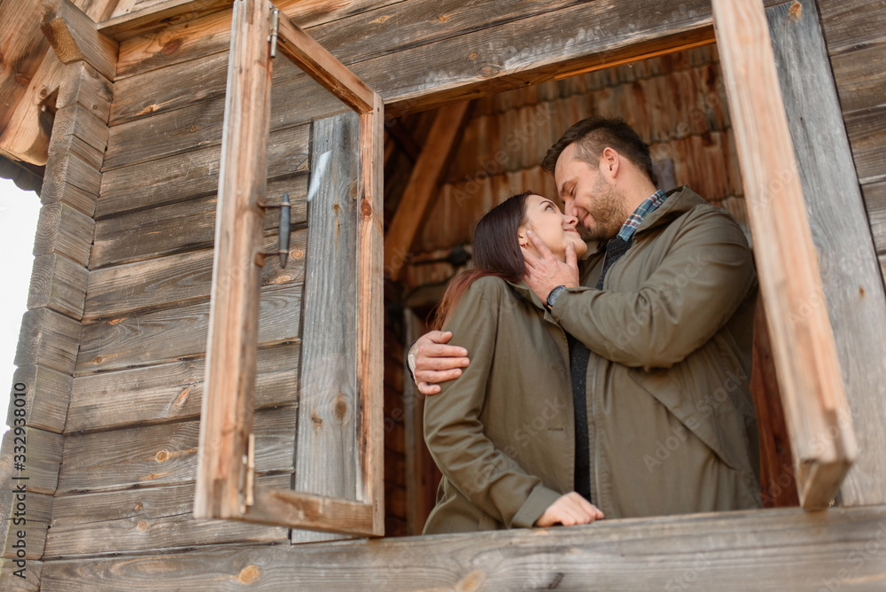 couple in love looks out of the window, wooden house. The concept of buying new housing for young families. couple in love looks out of the window, wooden house. The concept of buying new housing for young families.