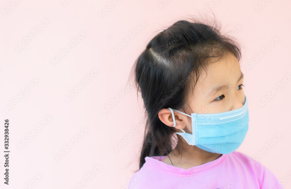 An Asian girl wearing a pink T-shirt stands wearing a sanitary mask. An Asian girl wearing a pink T-shirt stands wearing a sanitary mask.