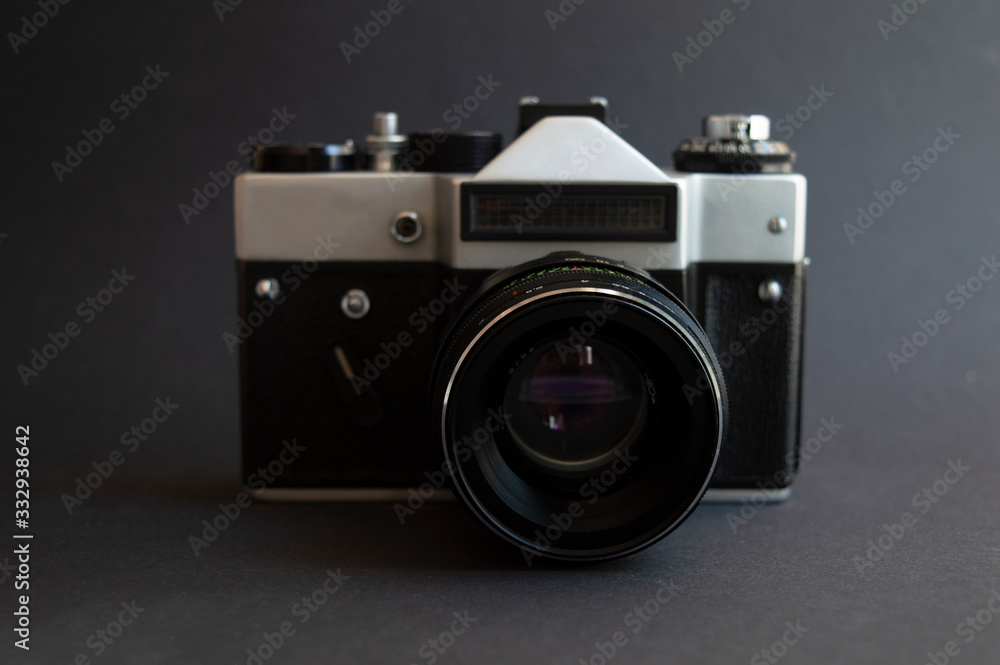 Vintage film photo camera on the dark background. Metal silver and plastic black frame with lens.