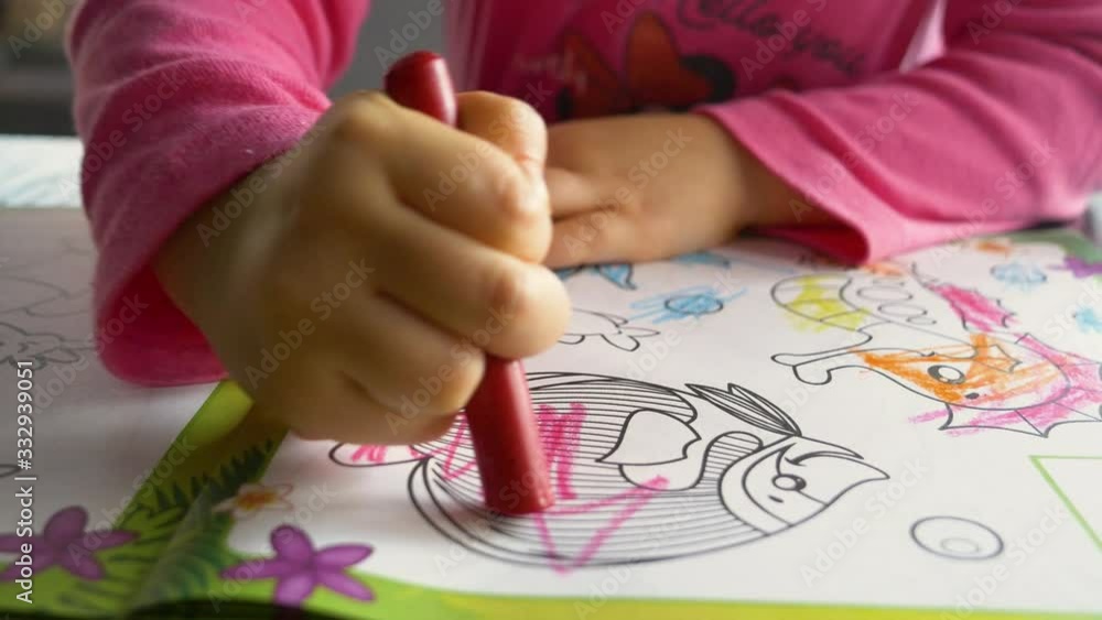 A three-year-old child paints a book with colored crayons A three-year-old child paints a book with colored crayons