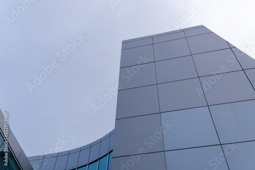 The upward view of modern aluminum metal composite panels to repair, restore, the facade of building. There are two shades of gray or grey on the wall. The grey sky of clouds are in the background.
