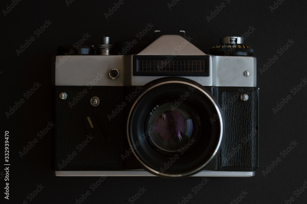 Vintage film photo camera on the dark background. Metal silver and plastic black frame with lens