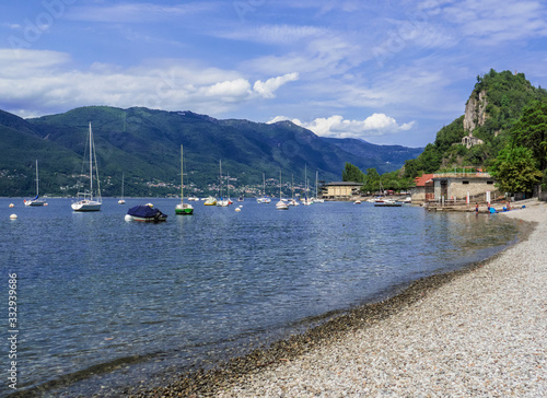 pebble beach on a clear summer day with sailing boats moored nearby. Lake Maggiore, italy photo