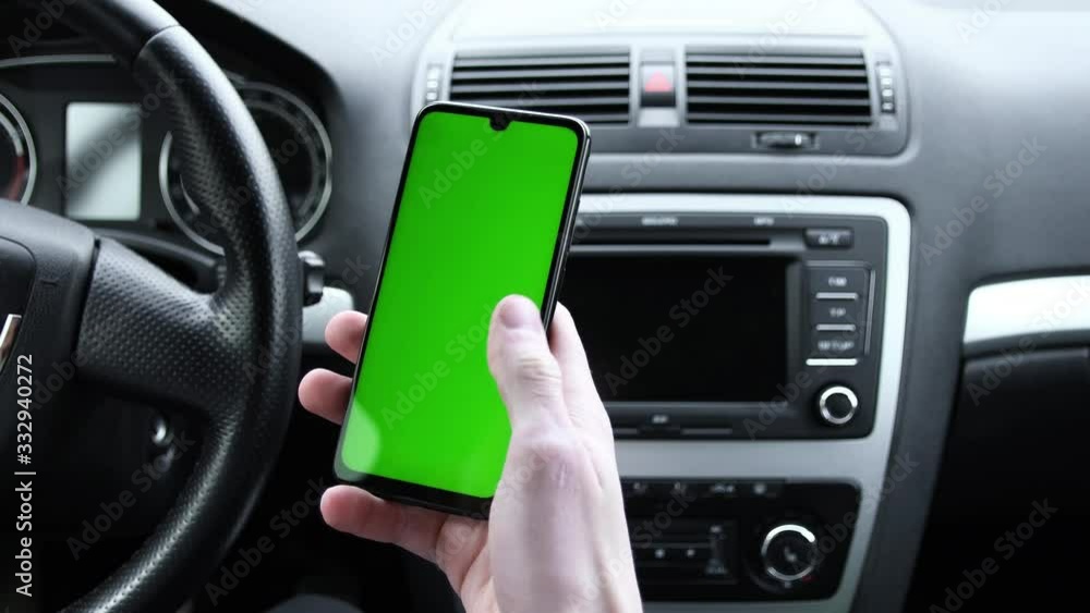 In the modern new car young man hand using smartphone , mobile phone with vertical green screen indooors.Internet Social Networks Browsing.Chroma key.Close up In the modern new car young man hand using smartphone , mobile phone with vertical green screen indooors.Internet Social Networks Browsing.Chroma key.Close up