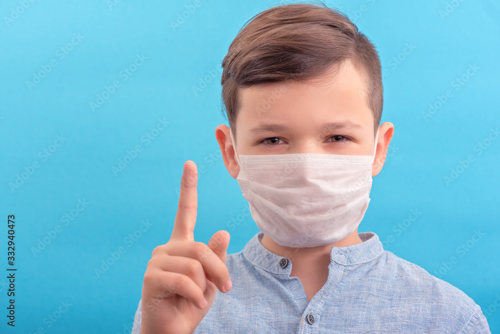 Brunette boy in medicine surgical mask showed attention. Be responsible and stay home