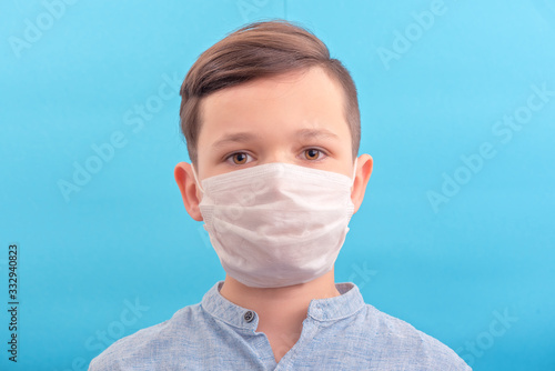 Handsome brunette boy in medicine face mask over blue background