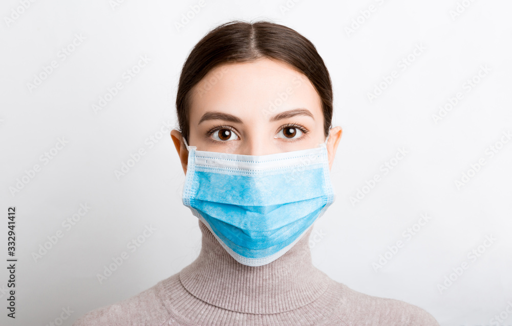 Portrait of young woman wearing medical mask at white background. Protect your health. Coronavirus concept Portrait of young woman wearing medical mask at white background. Protect your health. Coronavirus concept