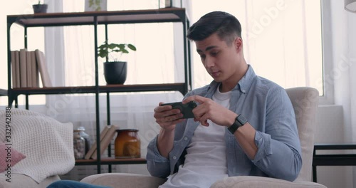 Amazed guy watching online videos on cellphone at home photo