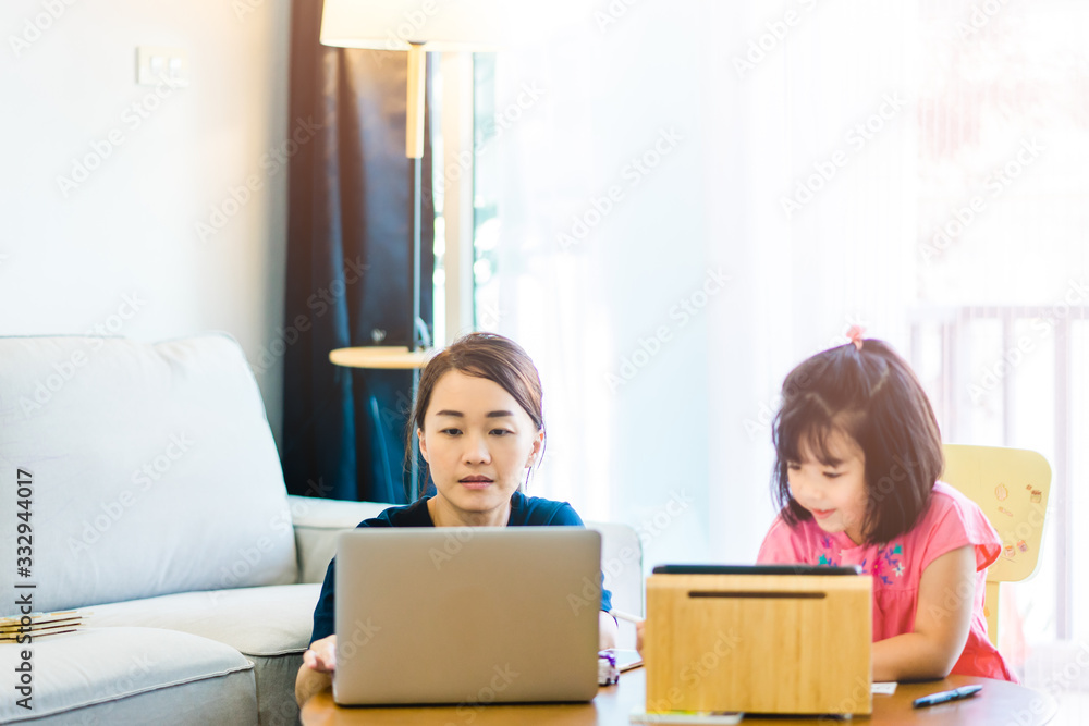 Covid-19 Coronavirus and Learning from home, Home school kid concept.Little asian girl study with online learning and asian mother work from home with laptop.Quarantine and Social distancing concept. Covid-19 Coronavirus and Learning from home, Home school kid concept.Little asian girl study with online learning and asian mother work from home with laptop.Quarantine and Social distancing concept.