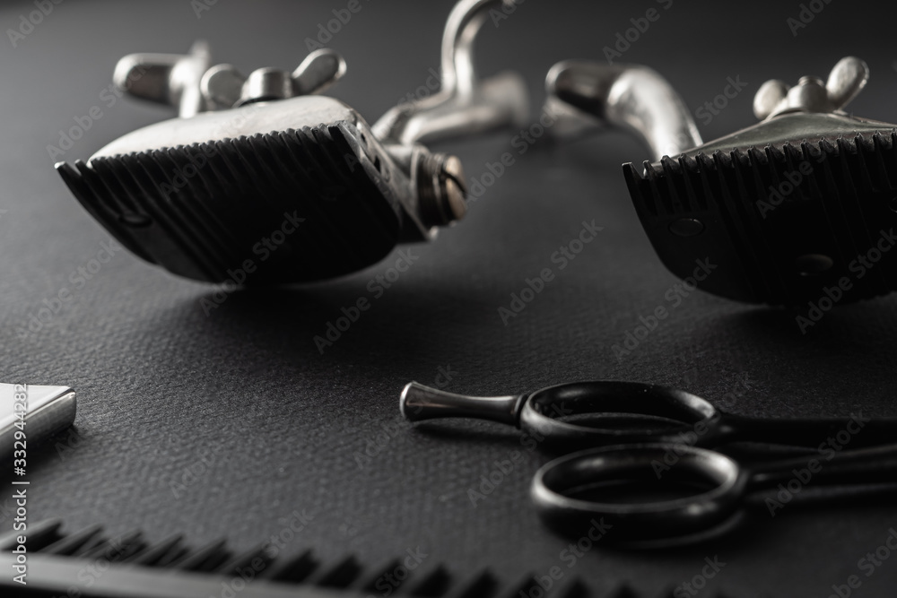 On a black surface are old barber tools. vintage manual hair clipper, razor, comb, hairdressing scissors. black monochrome. horizontal On a black surface are old barber tools. vintage manual hair clipper, razor, comb, hairdressing scissors. black monochrome. horizontal