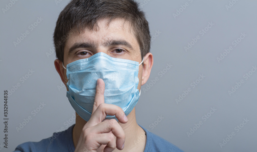 portrait of a man in a protective medical mask on face showing sign of silence gesture putting finger in mouth and lips, concept medical secrecy, moment of mourning and silence portrait of a man in a protective medical mask on face showing sign of silence gesture putting finger in mouth and lips, concept medical secrecy, moment of mourning and silence