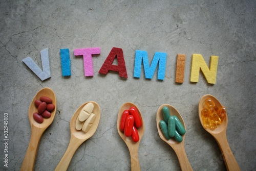 Vitamin capsules on wooden spoon. Vitamin B, C, zinc, iron, fish oil.
