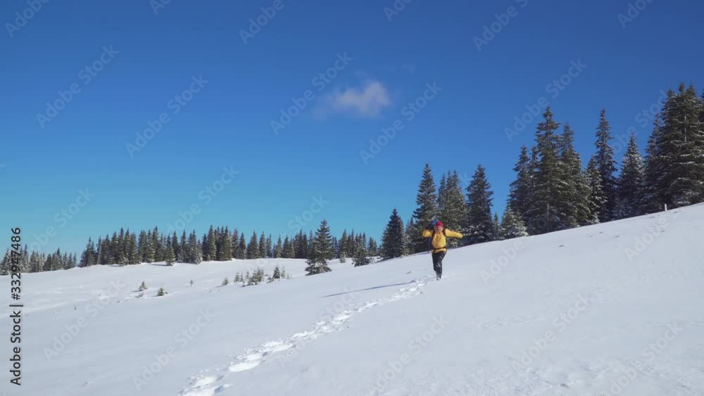 A man with a backpack travels in the mountains in winter. He is happy and joyful. Carpathian mountain range. The concept of travel and active lifestyle. 4K A man with a backpack travels in the mountains in winter. He is happy and joyful. Carpathian mountain range. The concept of travel and active lifestyle. 4K