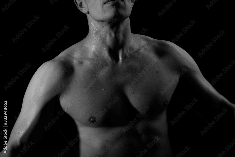 The pumped up body of a man. Black and white background. Sport. Clothing. Body. Beauty and fashion. The pumped up body of a man. Black and white background. Sport. Clothing. Body. Beauty and fashion.