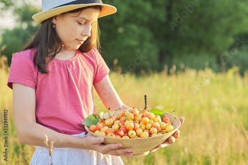 Child girl in hat with bowl of yellow sweet cherry, summer day in meadow © Valerii Honcharuk