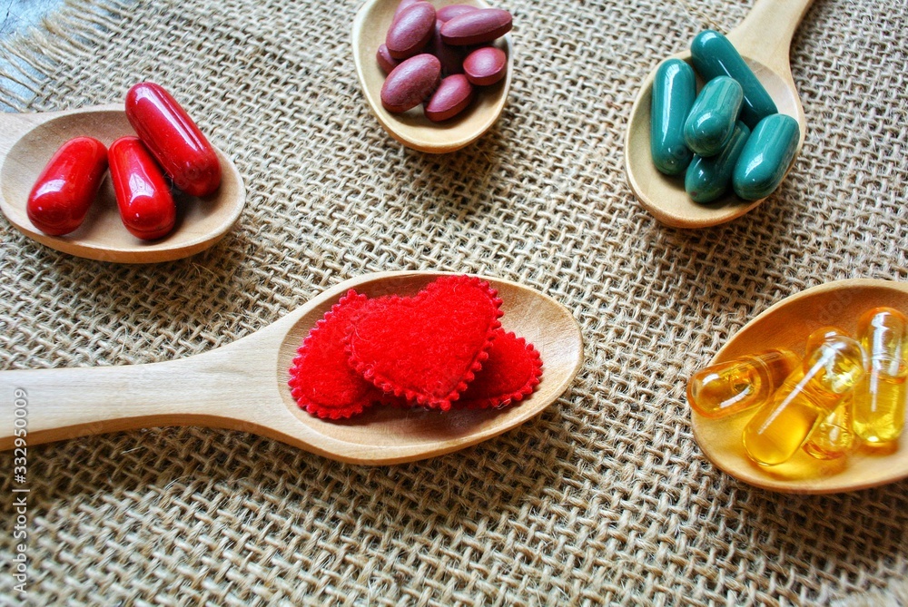 Vitamin capsules on wooden spoon. Vitamin B, C, zinc, iron, fish oil. Vitamin capsules on wooden spoon. Vitamin B, C, zinc, iron, fish oil.