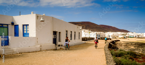tourist cycling in caleta de sebo street, la graciosa, canary islands