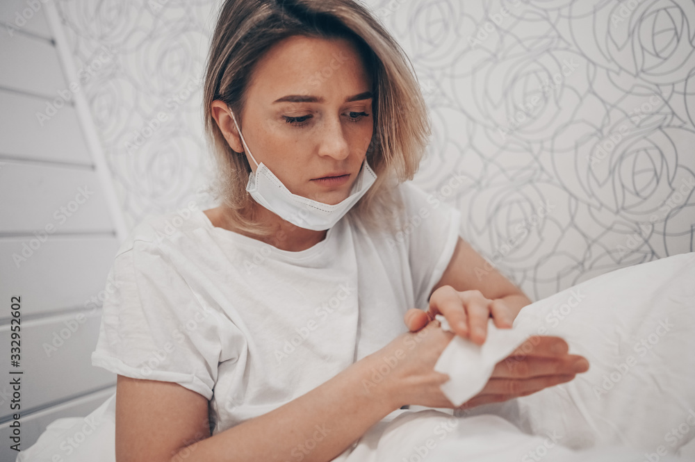 Woman in face protective mask lying in bed during coronavirus isolation