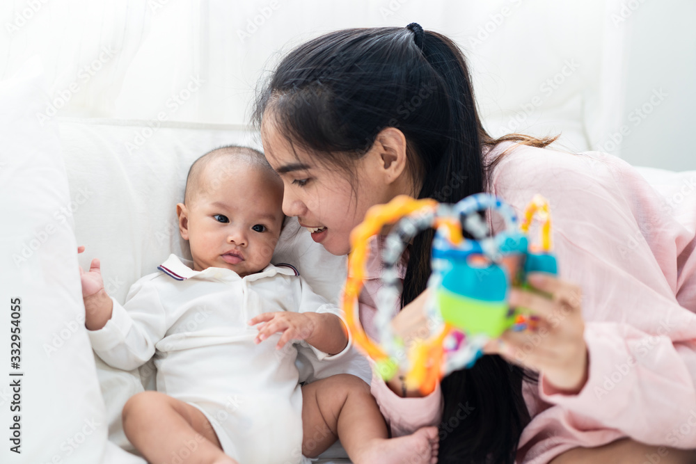 Asian cute baby and young mother playing toy on bed at home. Baby smiles and looks at toy feeling enjoy and happy with mom. Infant kid toy for education. Parent and baby skill development concept. Asian cute baby and young mother playing toy on bed at home. Baby smiles and looks at toy feeling enjoy and happy with mom. Infant kid toy for education. Parent and baby skill development concept.