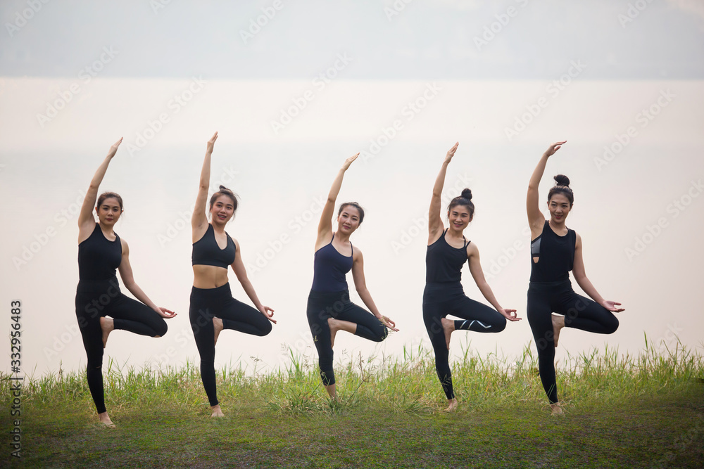 Asian Beautiful Women Group Doing yoga by the lake in the morning with warm sunshine Asian Beautiful Women Group Doing yoga by the lake in the morning with warm sunshine