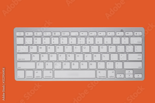 Wireless keyboard on an orange background. View from above. photo