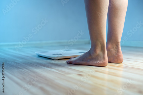 Women's bare feet stand on the floor electronic scales to check the weight and control the set of extra pounds