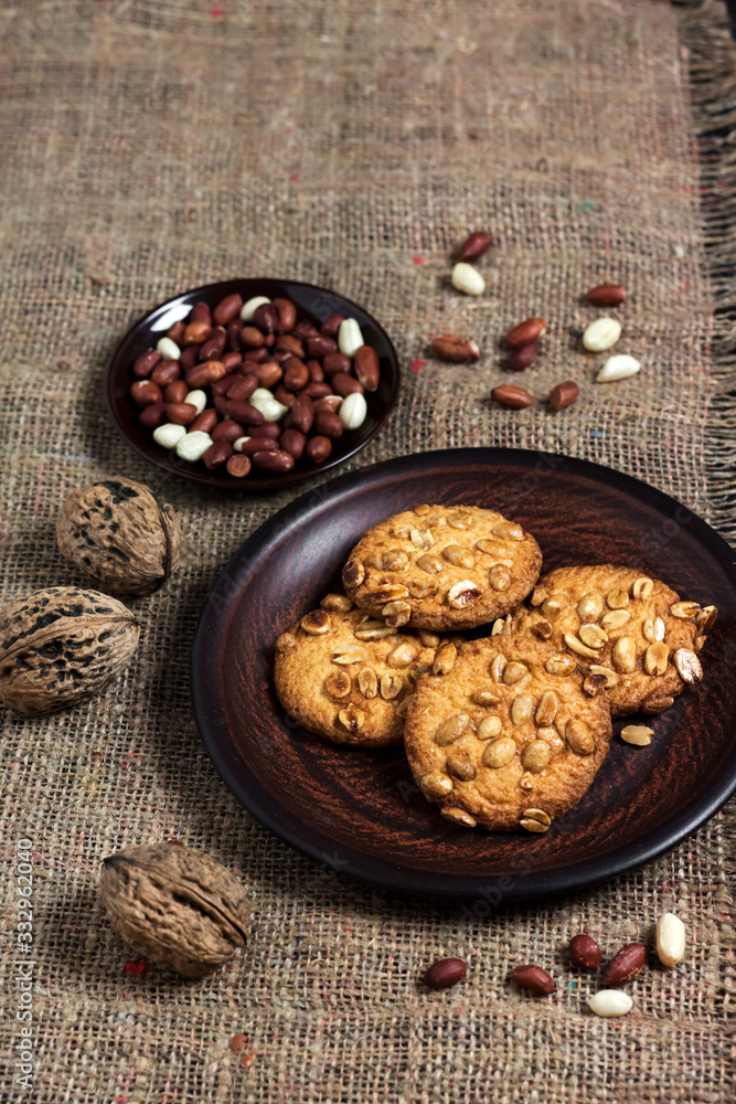 Homemade peanut cookies on a brown plate with raw peanuts in background