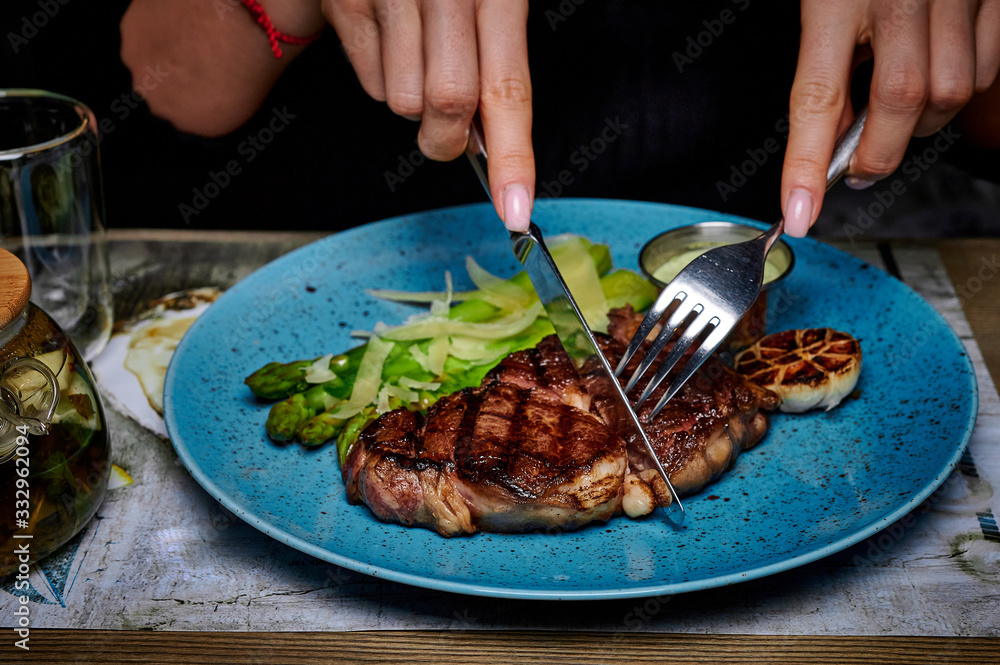 man eats steak in a plate on a table in a restaurant
