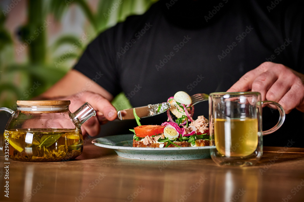 man eats caesar salad and drinks green tea