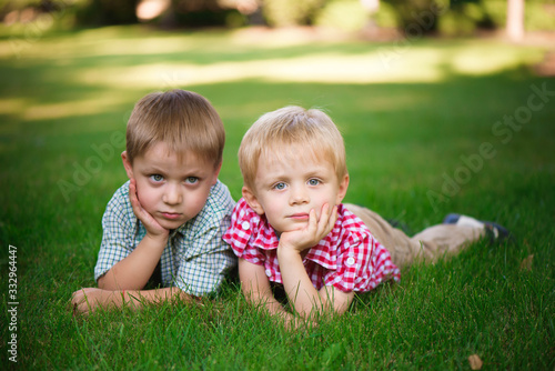 Two brothers lying on the grass in a park outdoors, smiling and
