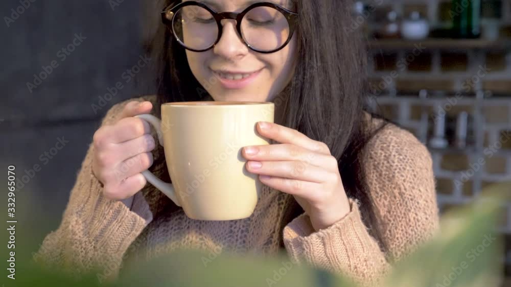 beautiful girl in stylish glasses raising the mug with hot chocolate to inhale the aroma beautiful girl in stylish glasses raising the mug with hot chocolate to inhale the aroma