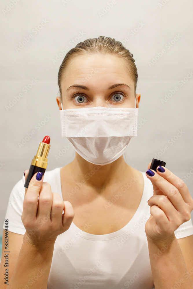 Close-up of young blonde in medical mask with lipstick in her hand