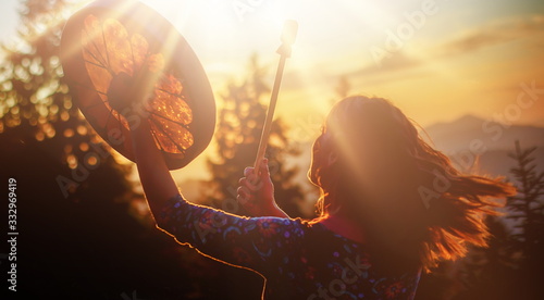 beautiful shamanic girl playing on shaman frame drum in the nature. photo