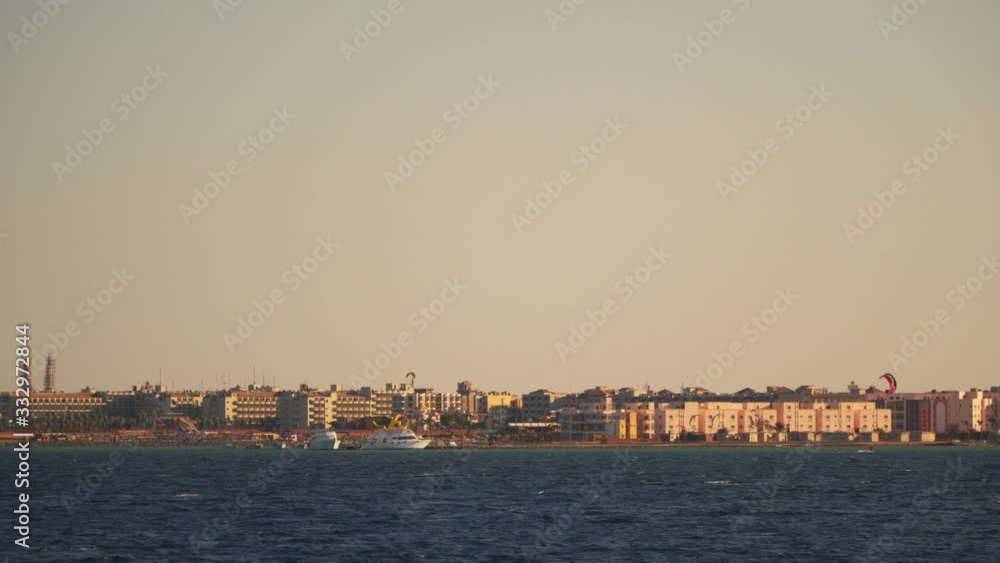 People doing kitesurfing near the coast. Evening time, view from a floating boat. Egypt People doing kitesurfing near the coast. Evening time, view from a floating boat. Egypt