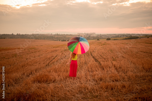 Young woman with multicolored umbrella standing in field